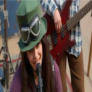 Female vocalist singing into a microphone during a rock band performance, with a bassist in the background